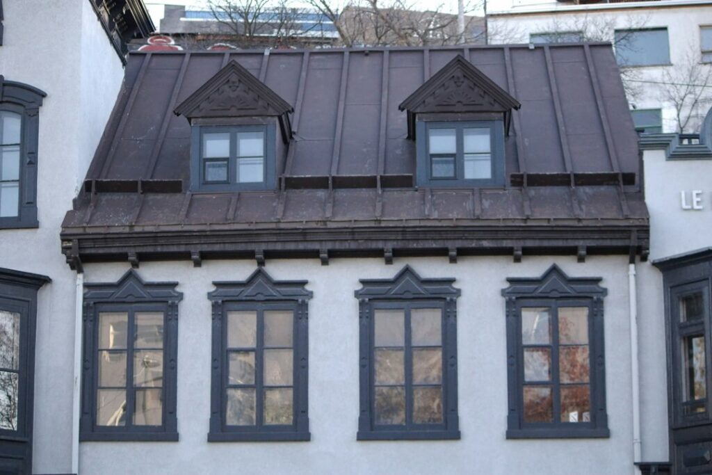 A residential roof showing slate, metal, tile, and asphalt materials during a snowy winter inspection.