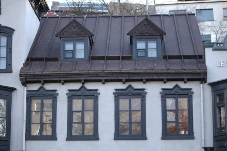 A residential roof showing slate, metal, tile, and asphalt materials during a snowy winter inspection.